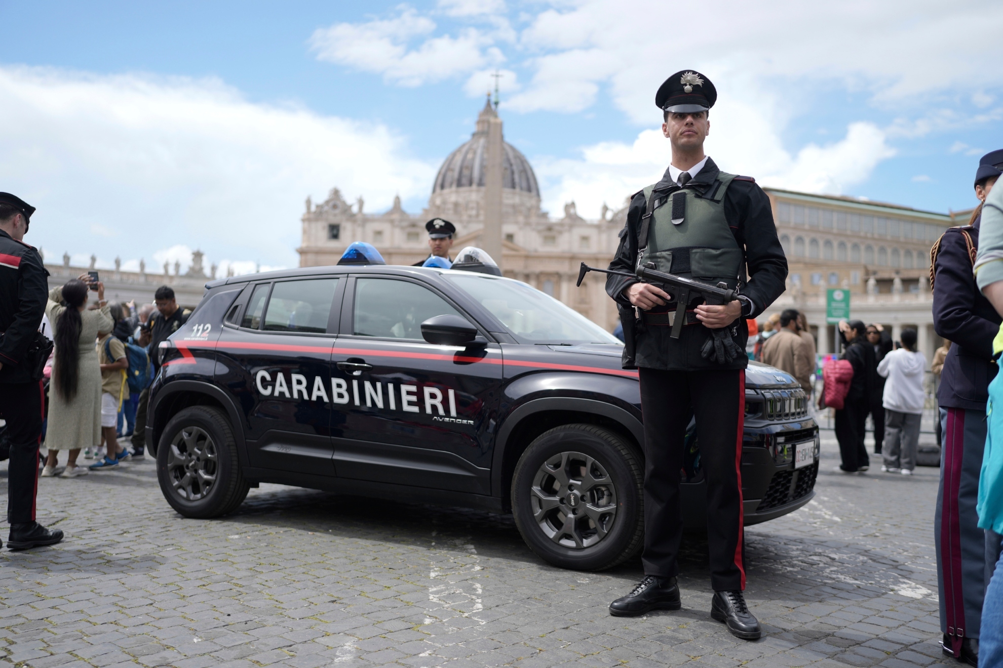 Un carabinieri hace guardia frente a un coche.